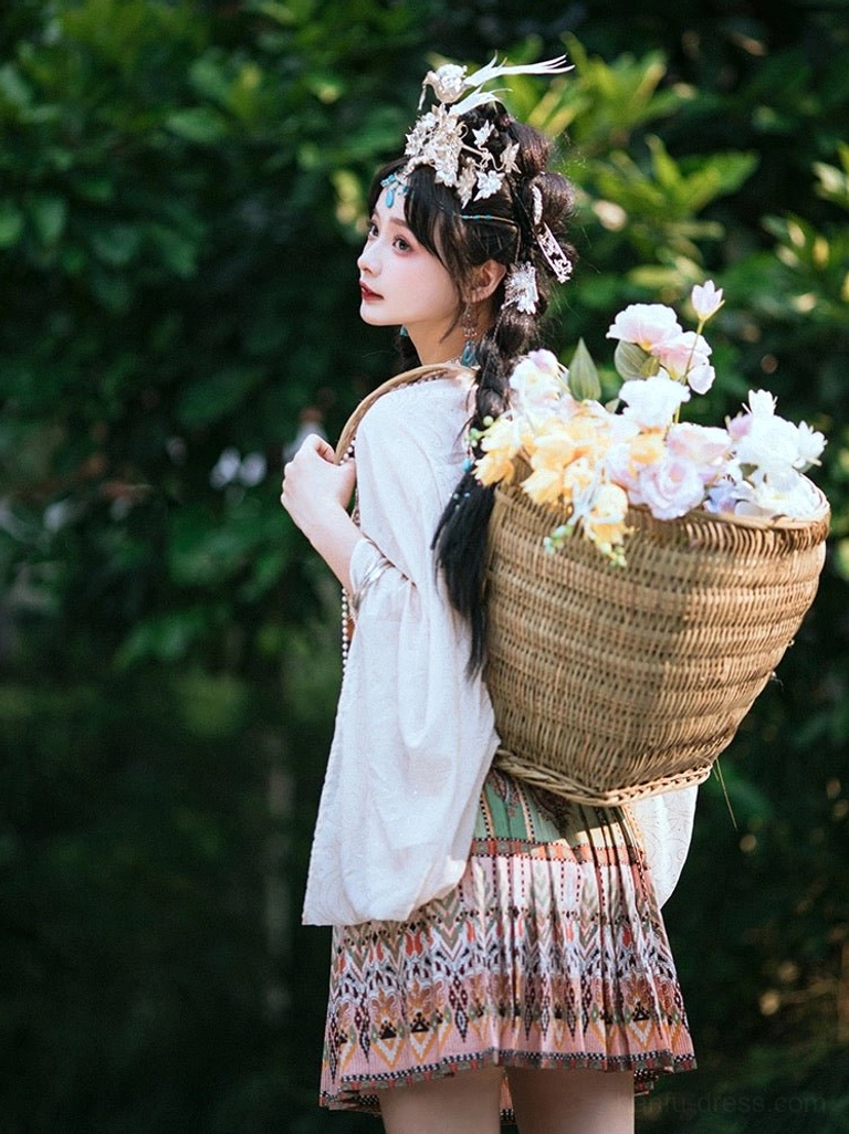 Back three quarter view of a Miao inspired Hanfu outfit showing the wide sleeve ivory coat dense ethnic embroidery and patterned pleated skirt