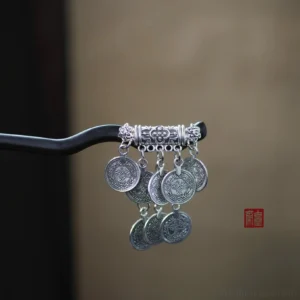Miao-inspired silver coin tassel Chinese hair stick with curved black shaft and ornate carved silver-tone crown front close-up
