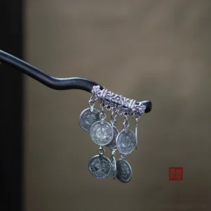 Side view of Miao-inspired Chinese hair stick showing curved dark pin and layered ancient coin style tassel charms