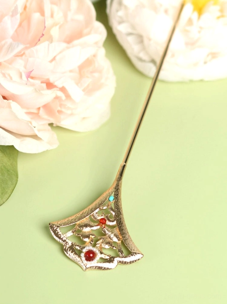 Close-up of a gold-toned Miaoling ginkgo leaf Hanfu hair pin with openwork floral carving, red beads, turquoise accents, and white pearl details arranged beside pink peony flowers