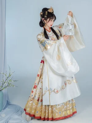 Ming Dynasty bridal Hanfu set in ivory and gold with red trim, model wearing traditional wedding hair ornaments and holding a white birdcage