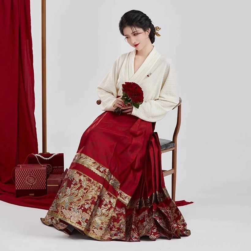 Seated bride wearing Ming Dynasty inspired red wedding Hanfu with winged sleeve top and gold hem mamian skirt for Chinese tea ceremony