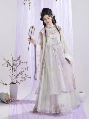 Three-quarter front view of a traditional Ming Dynasty Hanfu set with embroidered butterfly and floral motifs, cloud collar, flowing layered skirt, wide sleeves, and pastel lavender ivory colors