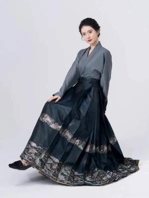 Ming-inspired Chinese Hanfu blouse and dark teal embroidered mamian skirt outfit shown in a seated three-quarter studio portrait