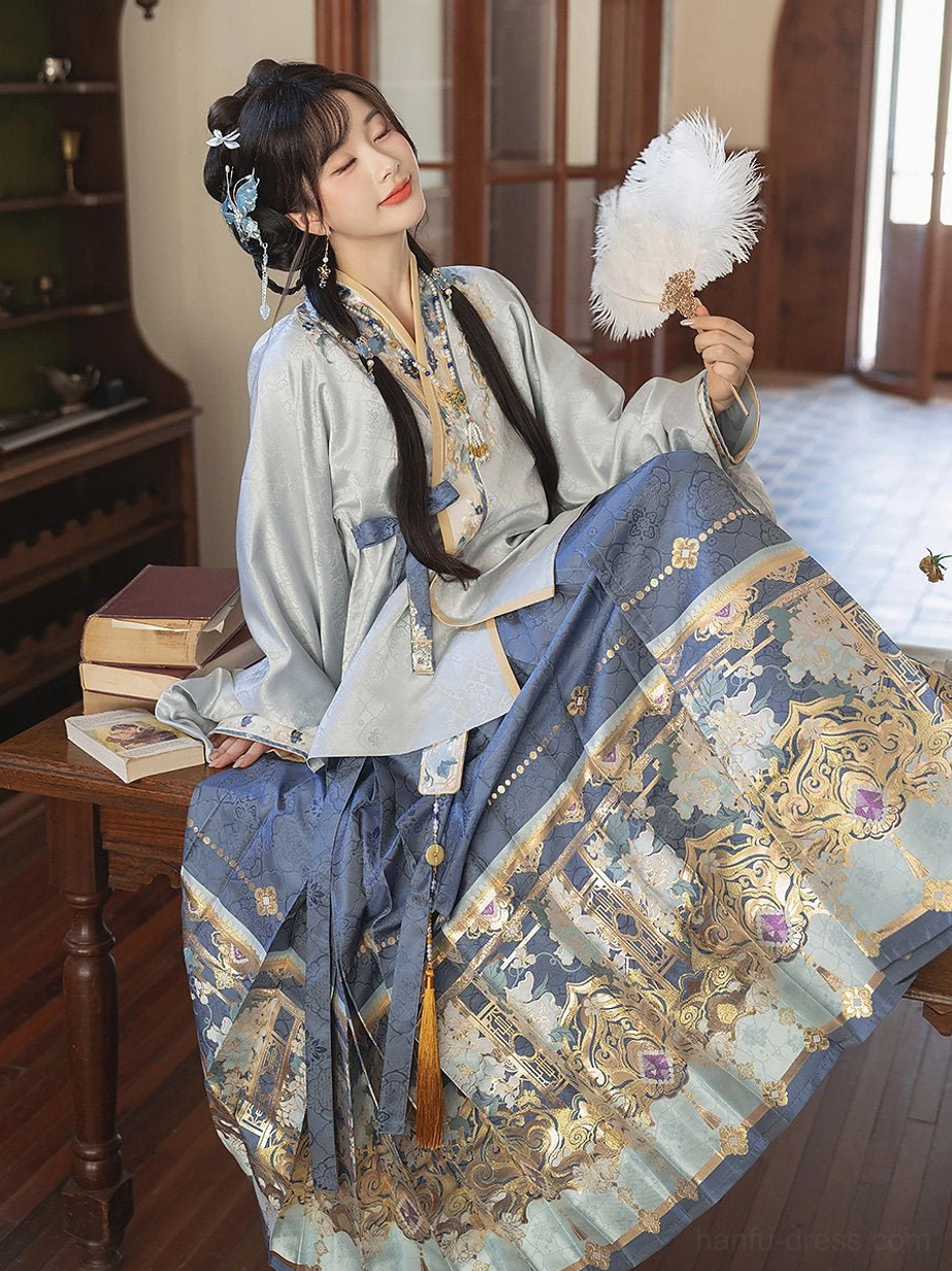 Ming Dynasty Hanfu set with pale blue cross-collar top, embroidered dark blue mamian skirt, blue waist sash, and traditional Chinese hairstyle in an elegant study setting