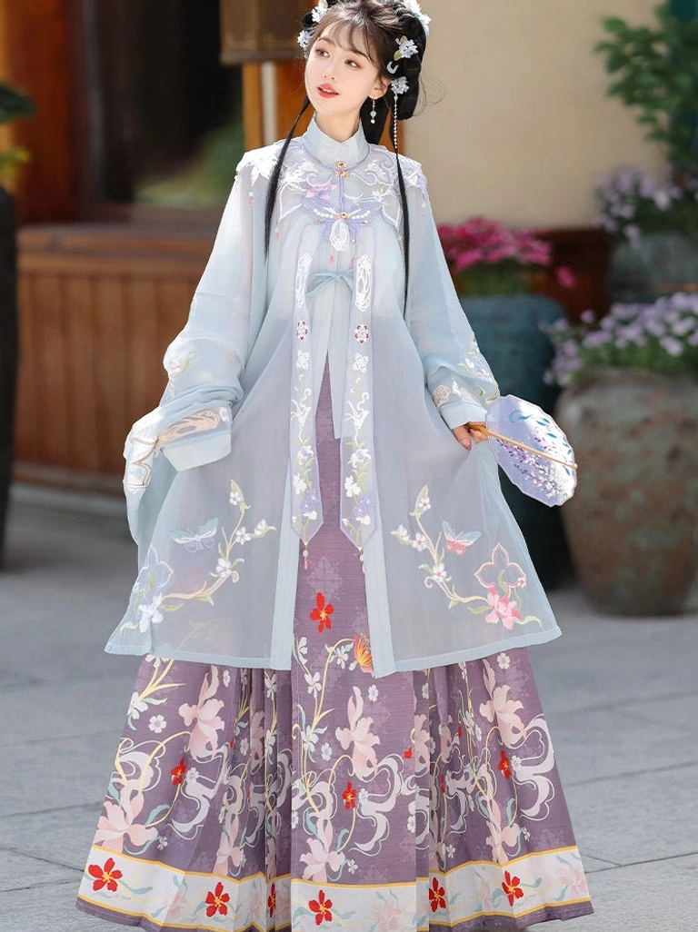 Ming Dynasty Hanfu blue embroidered blouse and purple floral mamian skirt shown from the side and back in a traditional courtyard garden