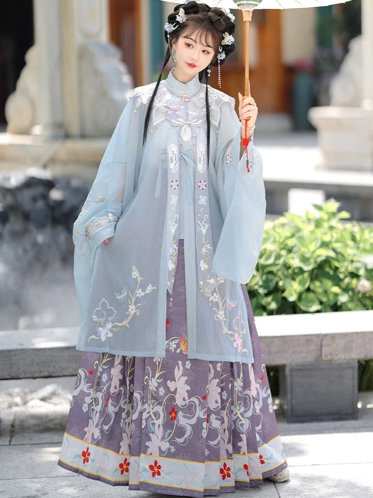 Ming Dynasty Hanfu blue stand collar blouse with subtle floral embroidery and purple mamian skirt with red decorative hem in a Chinese garden