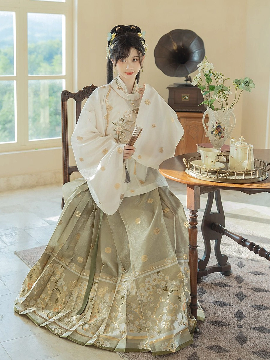 Ming Dynasty Hanfu outfit with ivory floral embroidered wide sleeve top and sage green Mamian skirt modeled in a vintage tea room