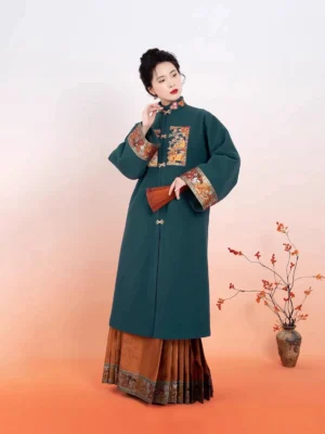 Three-quarter view of a traditional Ming Dynasty Hanfu outfit with a dark teal embroidered robe and brocade mamianqun skirt styled with a folding fan