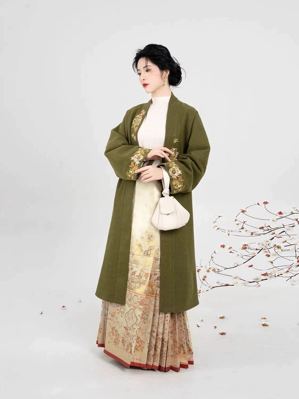 Full-length side view of a Ming Dynasty-inspired hanfu outfit with an olive-green embroidered coat and gold-patterned mamian skirt