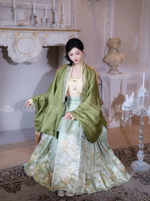 Ming Dynasty Hanfu outfit shown beside a vintage armchair with flowing pipa sleeves pleated jade green mamian skirt and golden floral details