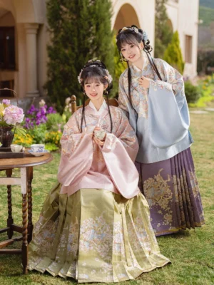 Two women wearing elegant Ming Dynasty Hanfu sets with pink and light blue pipa sleeve tops and embroidered Mamian skirts in a traditional garden setting