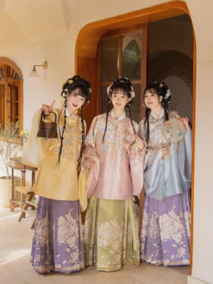 Three women modeling colorful Ming Dynasty Hanfu clothing sets with round-collar pipa sleeve tops and floral embroidered Mamian skirts indoors