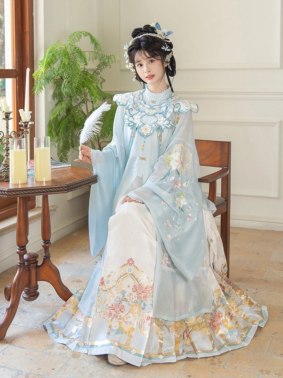 Seated three-quarter view of a woman wearing a pale cyan Ming Dynasty hanfu set with embroidered cloud collar, wide sleeves, and ivory Mamian skirt with gilt floral hem