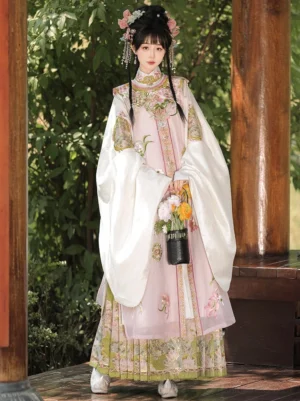 Ming Dynasty Hanfu set with pink embroidered robe white wide sleeves and green floral mamian skirt worn outdoors in a traditional garden pavilion