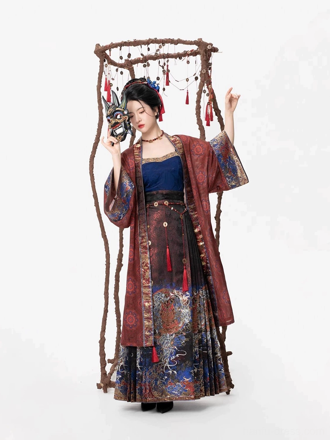 Side view of a modern Ming Dynasty Hanfu with wide reddish brown sleeves, dark blue layers, patterned skirt, and traditional Nuo mask