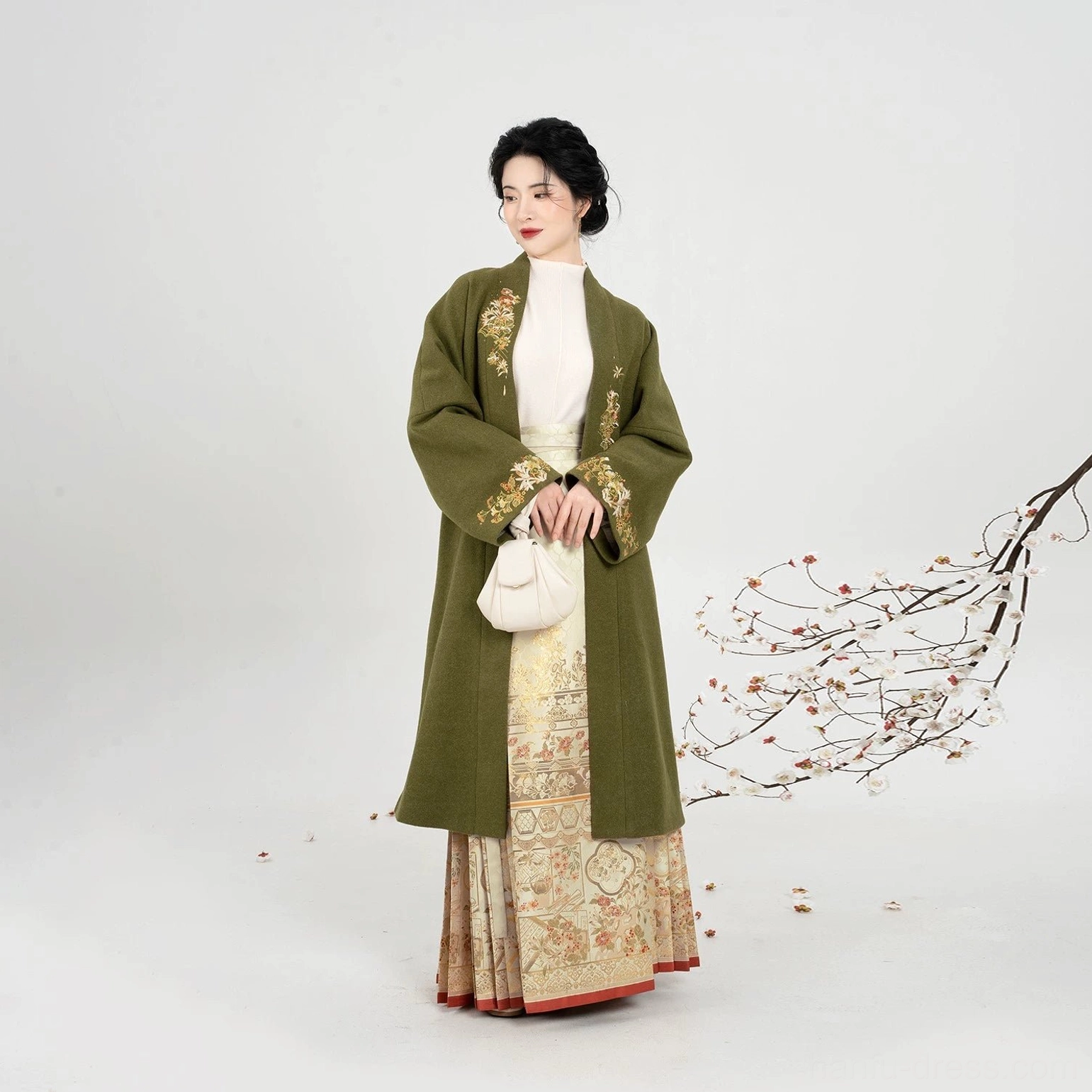 Full-length view of a model in a Ming Dynasty-inspired hanfu outfit with embroidered olive coat and gold mamian skirt
