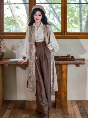 Full front view of a three-piece Ming Dynasty inspired hanfu outfit with off-white stand-up collar top, dark floral long robe, and high-waisted brown wide leg pants