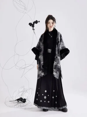 Full body front view of a model wearing a modern Ming Dynasty inspired black and white plaid Hanfu shawl with dark faux fur trim, styled with an embroidered black mamian skirt in a minimalist studio