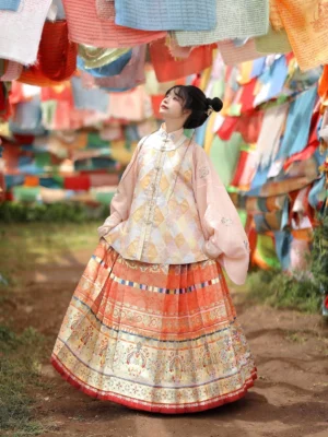 Pastel orange Ming Dynasty hanfu set with pipa sleeve top and pleated mamian skirt photographed outdoors with colorful prayer flags
