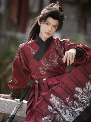 Front close-up view of a male model wearing a deep crimson Ming Dynasty Tie Li Hanfu robe with silver dragon and landscape prints, black cross collar, and traditional swordsman styling