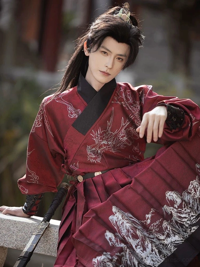Front close-up view of a male model wearing a deep crimson Ming Dynasty Tie Li Hanfu robe with silver dragon and landscape prints, black cross collar, and traditional swordsman styling