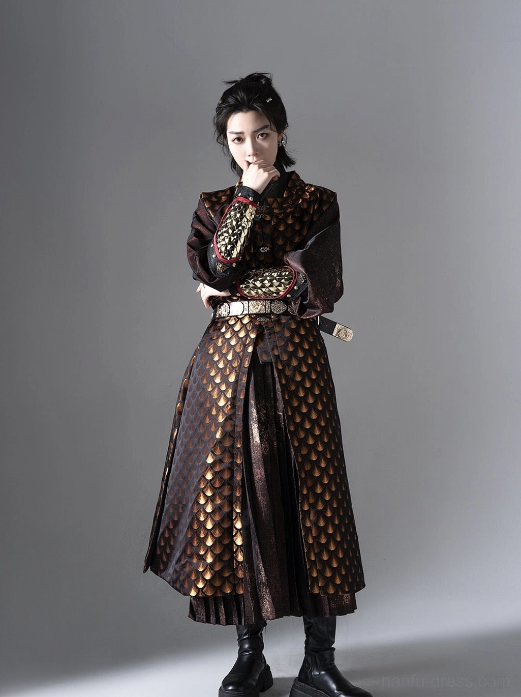 Three quarter view of a gender neutral Ming Dynasty Tieli Hanfu robe with golden scale jacquard vest waist belt sword ornament and pleated skirt