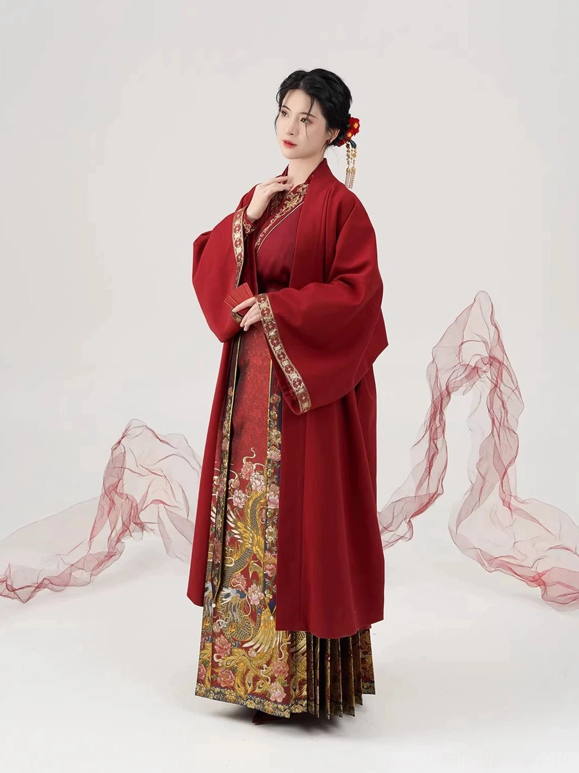 Close-up three-quarter view of a deep red Ming Dynasty wedding Hanfu overcoat with embroidered cuffs and decorated front placket