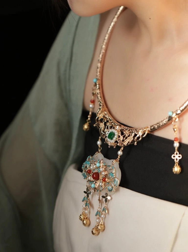 Ming-inspired Chinese necklace worn with Hanfu clothing, decorated with green and red gemstones, white jade-style lock pendant, gold filigree, and four-leaf hanging charm