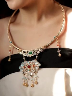 Ming-inspired Chinese wedding necklace worn on the neck with gold-tone metal, colorful gemstones, white jade-style lock pendant, filigree details, and dangling bell tassels