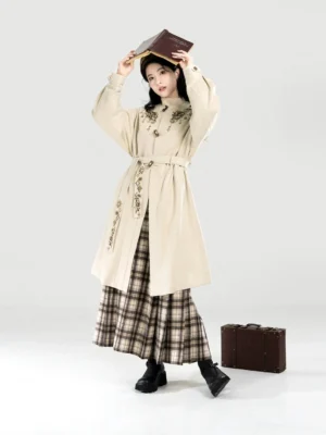 Full-length view of a beige embroidered Ming-inspired Hanfu coat styled with a brown plaid mamian skirt, beret, and black boots
