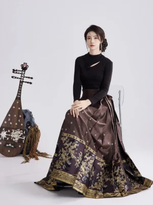 Ming-inspired Hanfu Mamianqun skirt set shown from the side while seated, highlighting the flowing floor-length pleats, golden embroidery, and satin-like brown fabric