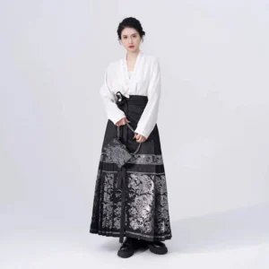 Front full-body view of a woman wearing a white cross-collar winged sleeve Hanfu top with a black silver floral Mamian skirt in a Ming-inspired Chinese traditional outfit