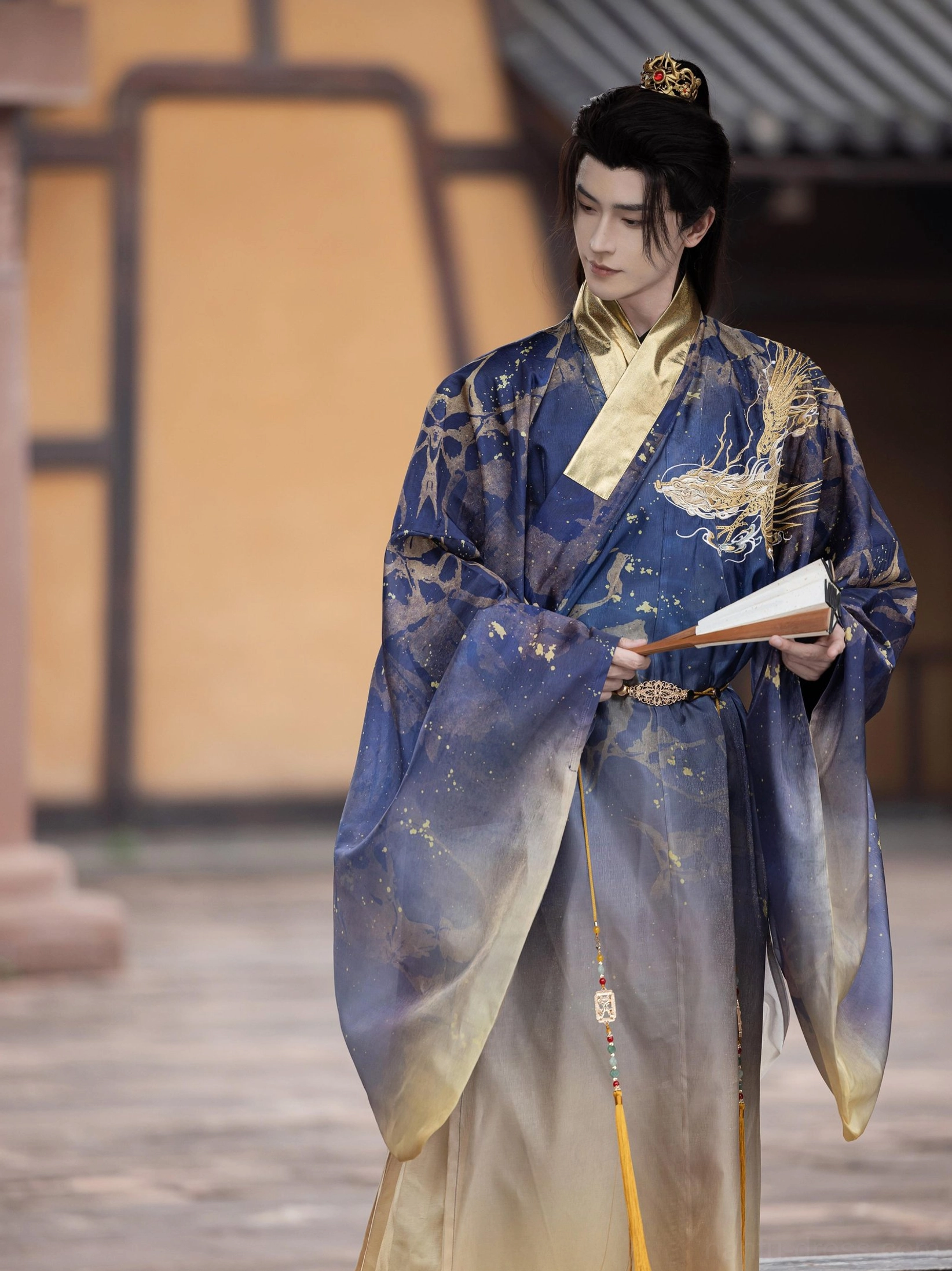 Full length side view of Ming Dynasty inspired men's Taoist robe with cross collar, gold trim, flowing blue to gold gradient and decorative tassels