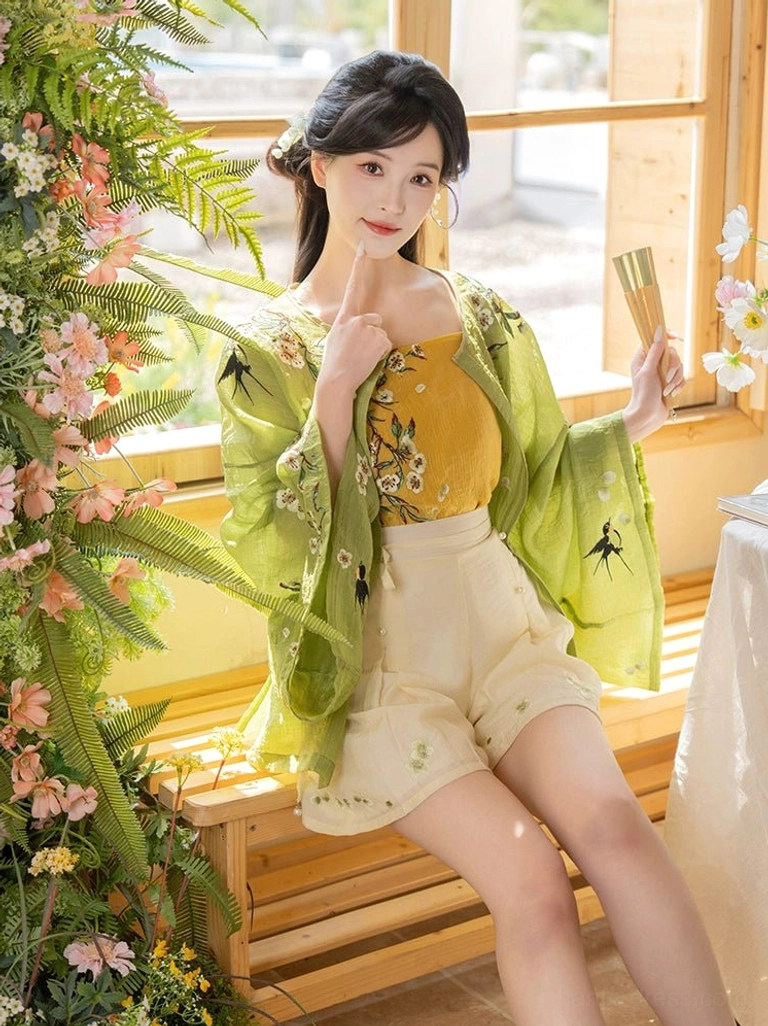 Ming inspired modern Hanfu three piece set styled with a folding fan and floral embroidered cardigan in a traditional garden interior