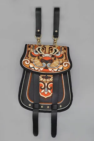Ming-inspired tiger embroidered Chinese diexie waist bag displayed flat on a gray background, showing the black microfiber leather base, colorful tiger face embroidery, gold-tone hardware, and decorative hanging straps