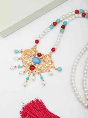 Top-down flat lay of a Ming-style Chinese Hanfu necklace pendant set with a carved gilded longevity lock, red and blue decorative stones, and small hanging pearl charms