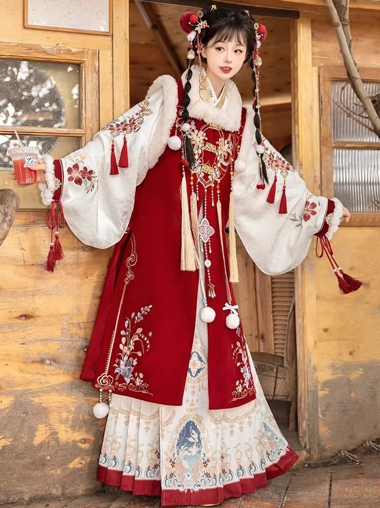 Side view of a Ming-style Chinese New Year hanfu dress with embroidered red waistcoat, decorative sleeve tassels, white pom-pom pendants, layered printed skirt, and red trim