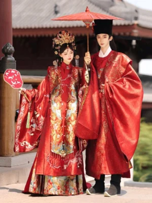 Traditional Ming style Chinese wedding Hanfu couple standing before an ancient pavilion, with ornate bridal embroidery, red groom robe, wedding umbrella, and silk fan