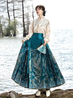 Front full-body view of a teal blue Ming style mamianqun Hanfu set with dragon and cloud jacquard horse-face skirt and light cross-collar top by a lakeside