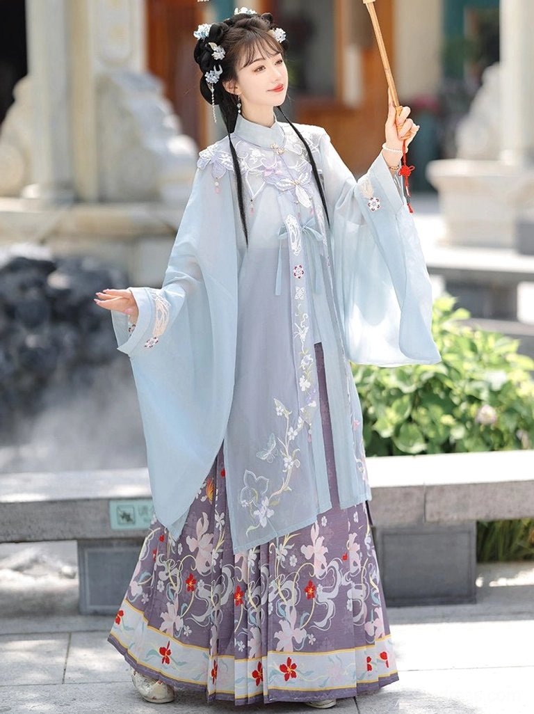 Light cyan Ming-style Hanfu blouse with sheer embroidered fabric and purple mamian skirt shown in side profile beside an oil paper umbrella