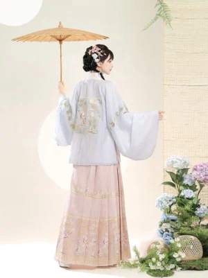 Back view of a traditional Chinese Ming-style hanfu outfit with embroidered pipa sleeve top, flowing pink mamian skirt, and oil paper umbrella