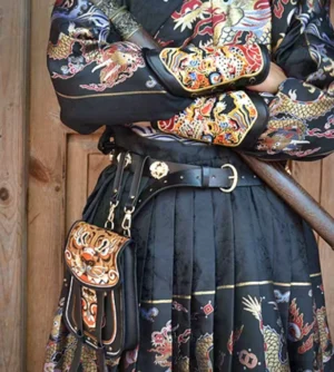 Ming-style Hanfu outfit with a tiger embroidered Chinese waist bag attached to a leather waist belt, photographed against a vintage wooden doorway with decorative hanging straps visible