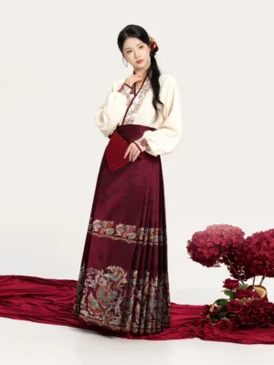 Three-quarter view of an elegant Ming-style hanfu outfit with winged sleeves, embroidered cuffs, pleated horse face skirt, and red traditional folding fan