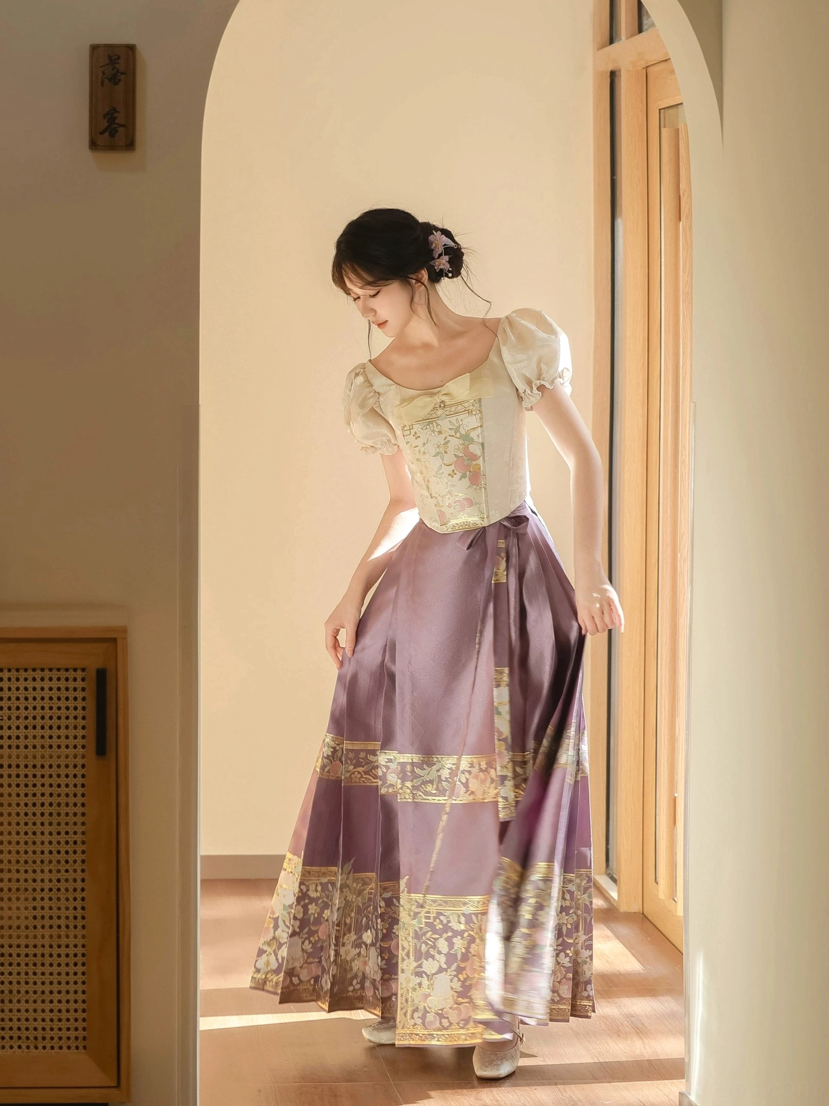 Ming style modern Hanfu two piece outfit with ivory embroidered puff sleeve corset and purple mamian horse face skirt in warm interior setting