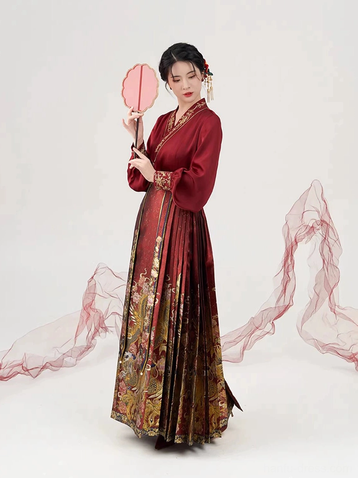 Ming wedding Hanfu inner top and pleated Mamian skirt shown from a side three-quarter angle with a traditional round red silk fan