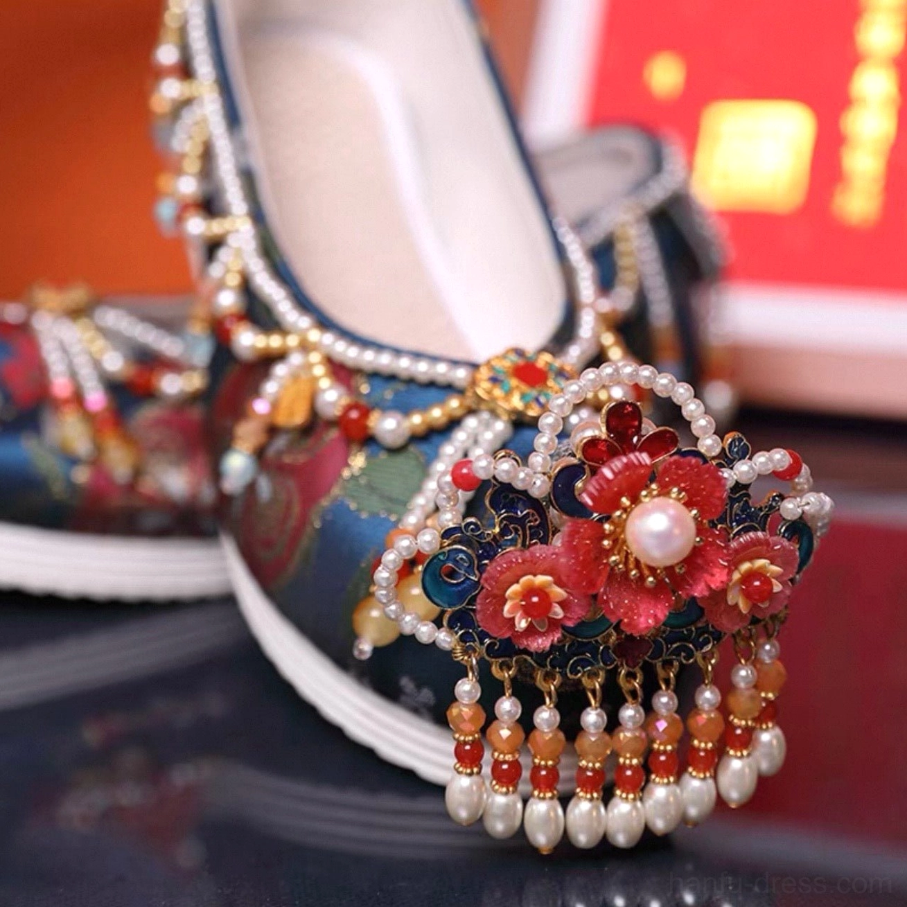 Close-up side view of blue traditional Chinese wedding shoe with pearl tassels red floral ornament metal details and white rubber sole