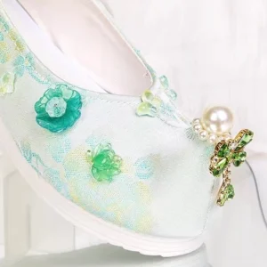 Close-up of mint green Chinese Hanfu platform shoe featuring pearl, green flower appliques, jeweled dragonfly toe ornament and white platform sole