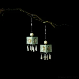 Mint green lattice tassel Chinese earrings for Hanfu displayed on a black background with a decorative tree branch