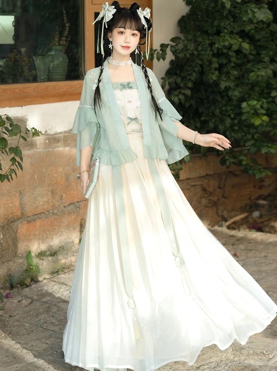 Back three-quarter view of mint green modern Song style Hanfu with off-white camisole wide pleated skirt light green sash and floral hair ornaments